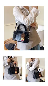 Detail of a black crocodile-patterned Boston bag with stylish knit doll pendant charm