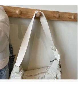 Dettaglio della borsa a tracolla in nylon crema con cinturino regolabile e zip scorrevole