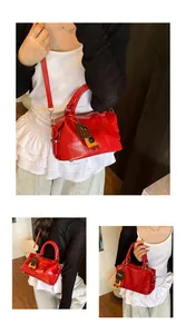 Detail of red croc-embossed bowling bag with adjustable strap and cute bear pendant