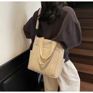Dettaglio della borsa tote grande in tela crema con tracolla regolabile su modella