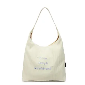 Borsa tote in tela color crema con ricamo blu e tracolla larga dal design minimale