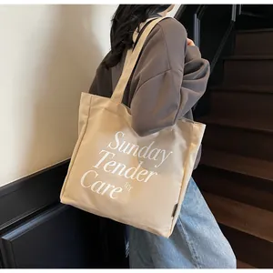 Dettaglio della stampa testuale su una borsa tote in tela beige con tracolle lunghe