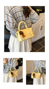 Three-way view of light yellow croc-embossed handbag with cute brown doll charm