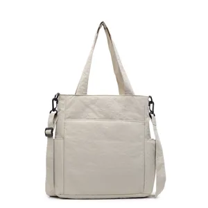 Borsa tote minimalista in tela beige con tasche multiple e tracolla regolabile su sfondo bianco