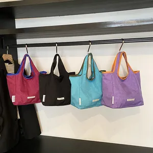 Large nylon tote bags in four colors hanging on a rack for a minimalist casual style