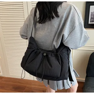 Dettaglio della borsa a tracolla in nylon nero plissettato con chiusura a coulisse
