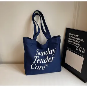 Dettaglio della borsa tote in tela blu navy con scritte Sunday Tender Care in bianco