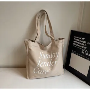 Dettaglio della stampa Sunday Tender Care sulla borsa tote minimalista in tela beige
