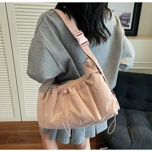 Dettaglio della borsa a tracolla in nylon a pieghe rosa chiaro con fibbia sul modello