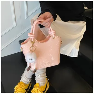 Détail d'un sac à main rose motif serpent avec boucles dorées et breloque peluche