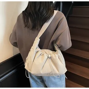 Dettaglio della borsa a tracolla in nylon beige con design a pieghe e fibbia regolabile