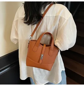 Borsa a secchiello marrone in pelle con chiusura in metallo argento su modella