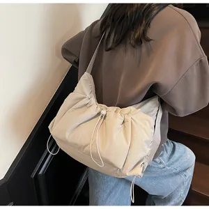 Vista della modella sul retro della borsa a tracolla in nylon beige con pieghe