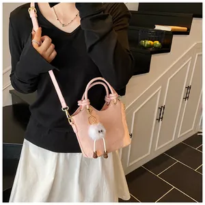 Détail du sac rose à motif serpent avec breloque en peluche sur un escalier moderne