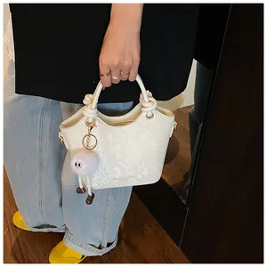 Détail du sac à main blanc motif serpent avec poignée nouée et breloque peluche