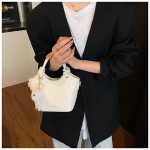 Détail d'un sac à main blanc à motif serpent avec breloque pelucheuse et métal doré