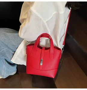 Dettaglio borsa a secchiello in pelle rosso con chiusura argento e tracolla rimovibile