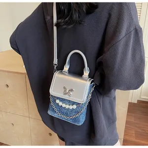 Vista posteriore di una modella con mini borsa a tracolla Y2K in denim con perle e farfalla