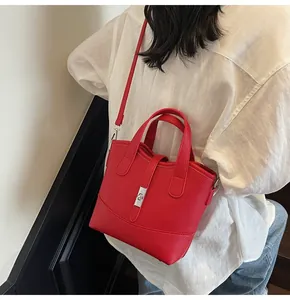 Dettaglio borsa in pelle litchi rossa con fibbia argentata e tracolla regolabile
