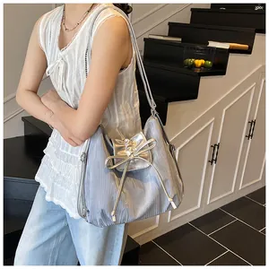Detail of silver pleated shoulder bag featuring a large bow and metallic finish