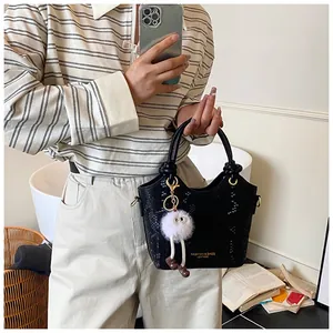 Détail du sac à main noir motif serpent avec pompon blanc et logo doré élégant