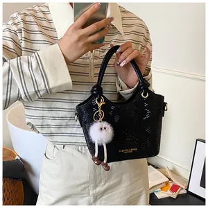 Détail d'un sac seau noir motif serpent avec boucles dorées et breloque peluche monstre