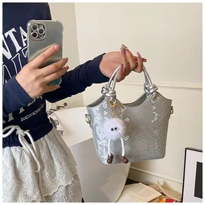 Détail du sac cabas argenté à motif serpent avec anse nouée et breloque en peluche