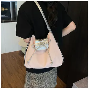 Detail of light pink hobo bag featuring silver bow accent and metallic shoulder strap