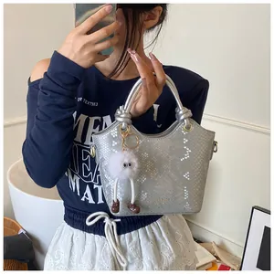 Détail d'un sac à main argenté effet serpent avec texture métallique et charm peluche