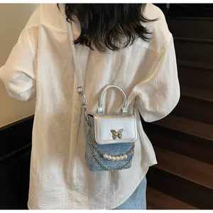 Dettaglio della mini borsa a tracolla argento e denim blu con farfalla e perline