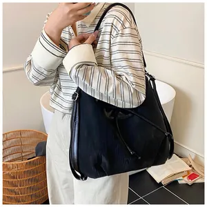 Detail of a large black tote bag with drawstring texture and adjustable shoulder strap