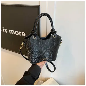 Détail d'un sac seau noir motif serpent avec finitions dorées et poignées nouées