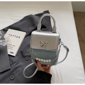 Dettaglio della mini borsa a tracolla con fibbia a farfalla argentata e catena di perle