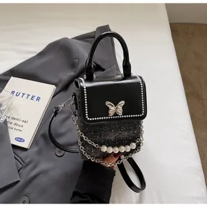 Dettaglio mini borsa a tracolla con chiusura a farfalla, tessuto tweed e catena di perle