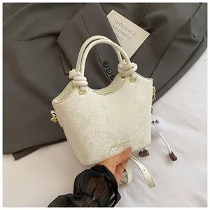 Détail du sac à main crème motif serpent avec poignée nouée sur un blazer gris chic