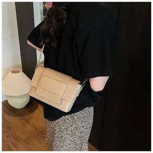 Dettaglio di una borsa a tracolla beige minimalista in pelle indossata da una modella