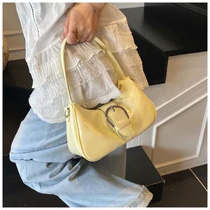 Dettaglio borsa a mezzaluna giallo pallido con fibbia argento indossata da modella
