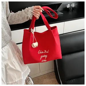 Détail macro du sac cabas en toile rouge avec broderie blanche et pendentif cordon chic