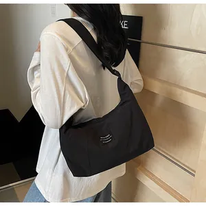 Dettaglio della grande borsa tote nera in nylon con etichetta tessuta e tracolla larga