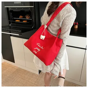 Vue détaillée d'un sac cabas en toile rouge avec lettrage blanc et pendentif à nœud