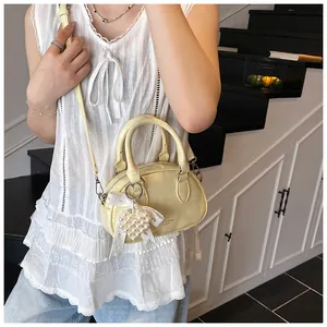 Detail of cream yellow crossbody bag with pearl heart charm and lace bow decoration