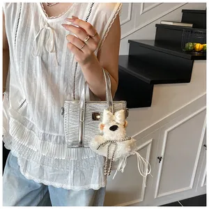 Close-up of silver glitter handbag featuring a cute plush bear charm with pearl details