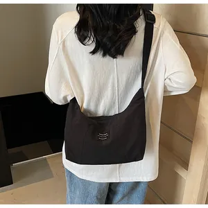 Vista dettagliata della borsa a tracolla in nylon nero con etichetta bianca indossata