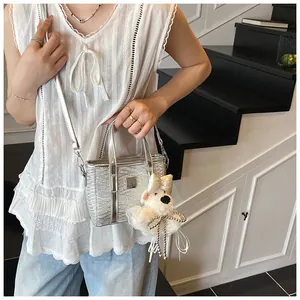 Close-up of silver pleated mini bucket bag with metallic finish and white bear charm