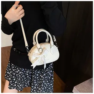 Close-up of white patent leather bowling bag with lace bow and adjustable shoulder strap