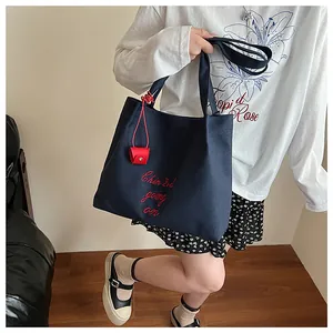 Détail du sac cabas en toile bleu marine avec broderie rouge et mini pochette assortie