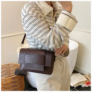 Borsa a tracolla rettangolare marrone scuro con patta a strati indossata da una modella