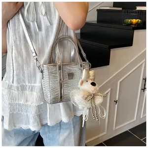 Detail of silver metallic mini tote bag with wavy texture and plush puppy charm