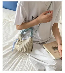 Dettaglio di borsa in paglia con manico a pieghe blu e fiocco in pizzo elegante