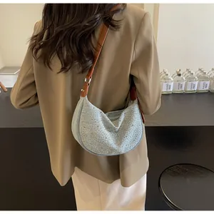 Dettaglio della borsa a mezzaluna in denim blu con strass lucidi e tracolla in pelle